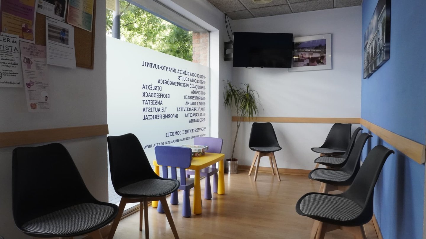 Sala de espera del centro Psicoat con sillas de adultos y mesa infantil junto al escaparate