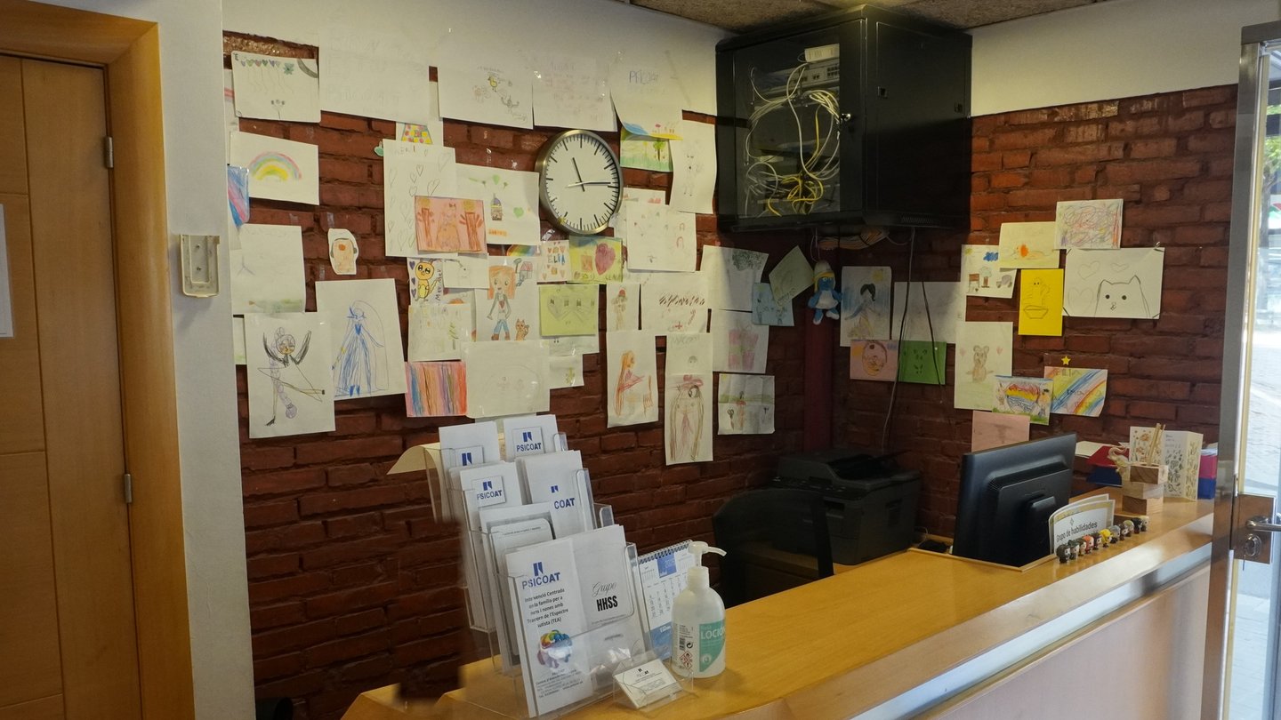 Mostrador de recepción de Psicoat con la pared de dibujos infantiles al fondo
